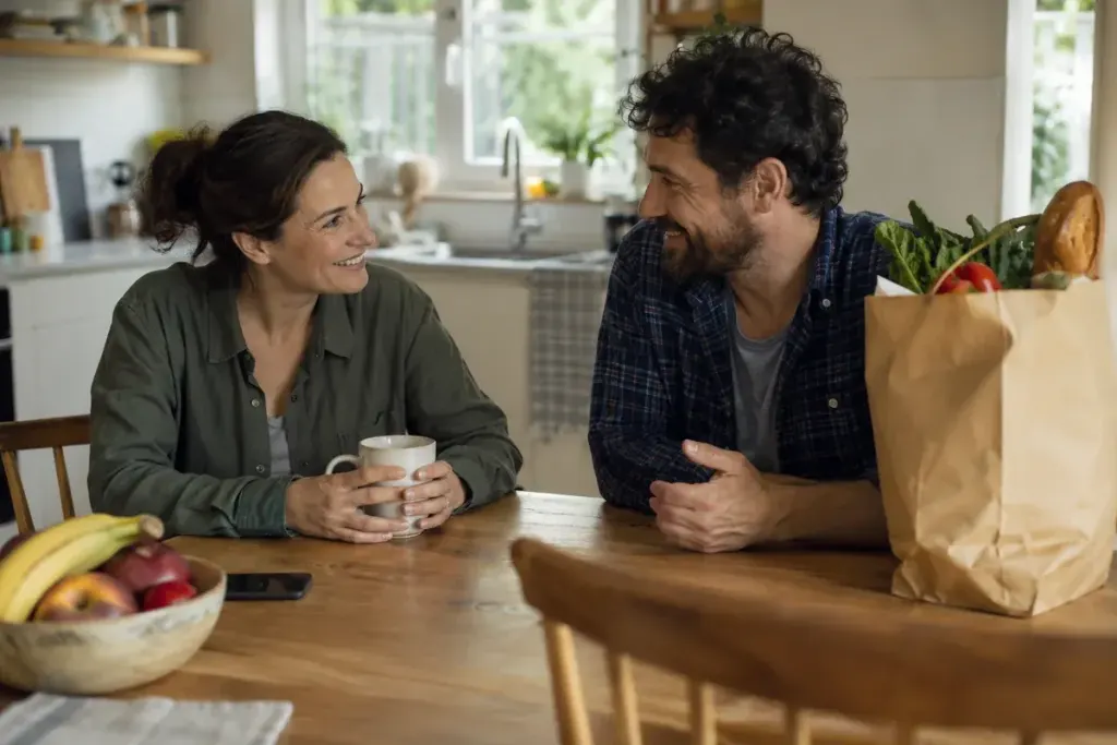 Two adults discussing practical help at a kitchen table.