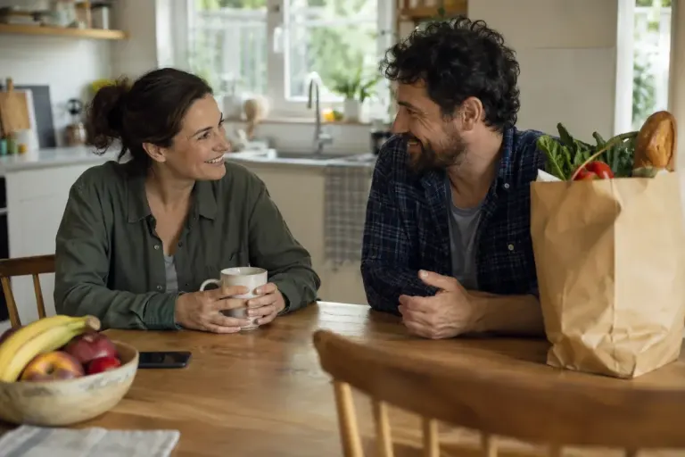 Two adults discussing practical help at a kitchen table.